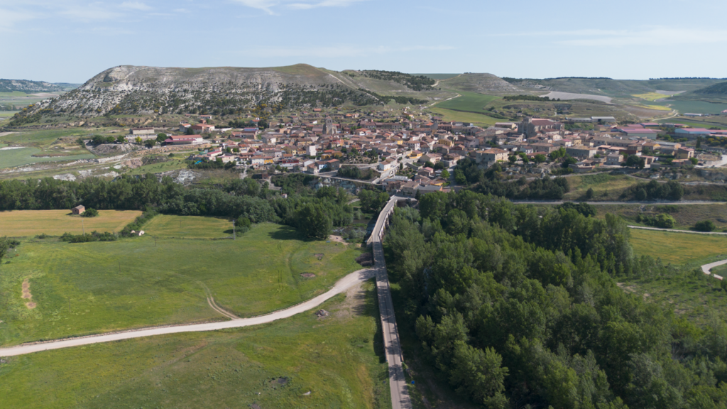 Panorámica aérea de Palenzuela, con el puente medieval en primer término. Al fondo el cerro en el que se encuentran los restos de la antigua ciudad prerromana de Pallantia.