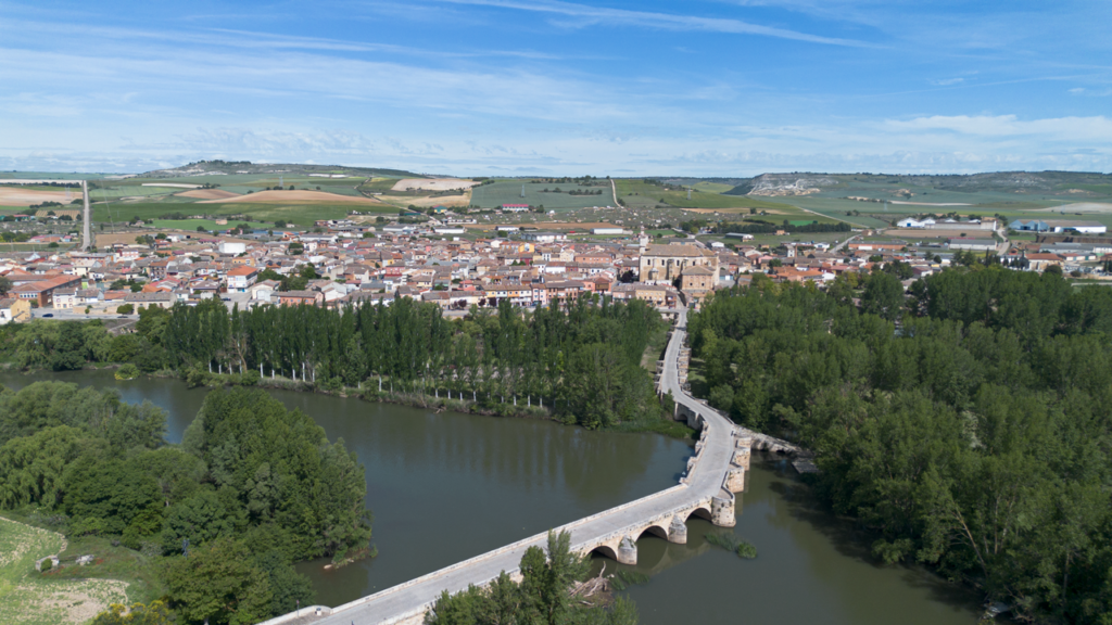 Panorámica aérea de Torquemada. En primer término el puente medieval sobre el río Pisuerga, a continuación la iglesia de Santa Eulalia y al fondo el barrio de bodegas.