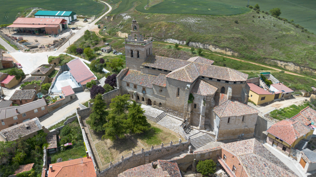 Panorámica aérea de la iglesia de Santa Columba de Villamediana. Se asienta a media ladera y es de grande proporciones y nave de crucería, con una torre a sus pies rematada por una espadaña.