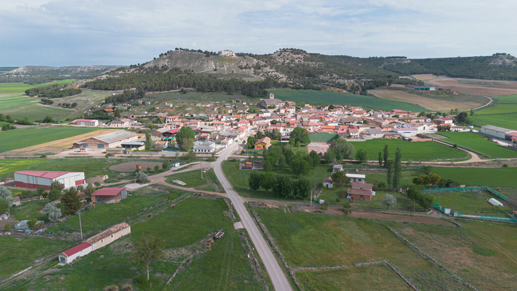 Panorámica aérea de Cubillas de Cerrato. Se aprecia la iglesdia rodeada por las bodegas y al fondo el cerro con las ruinas del castillo.