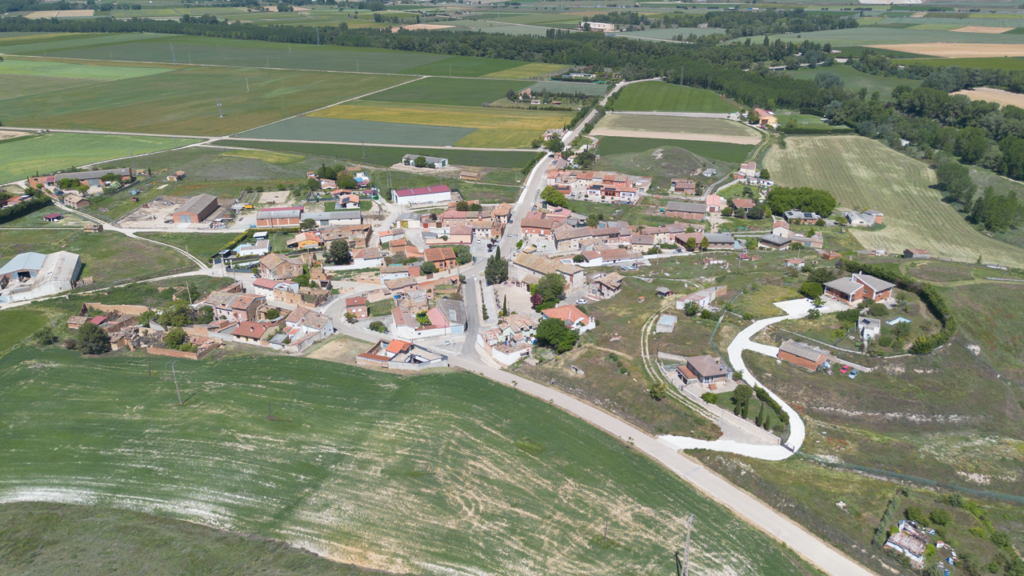 Panorámica aérea de Reinoso de Cerrato. En primer termino la iglesia y el barrio de bodegas y al fondo la línea de árboles marca el curso del río Pisuerga.