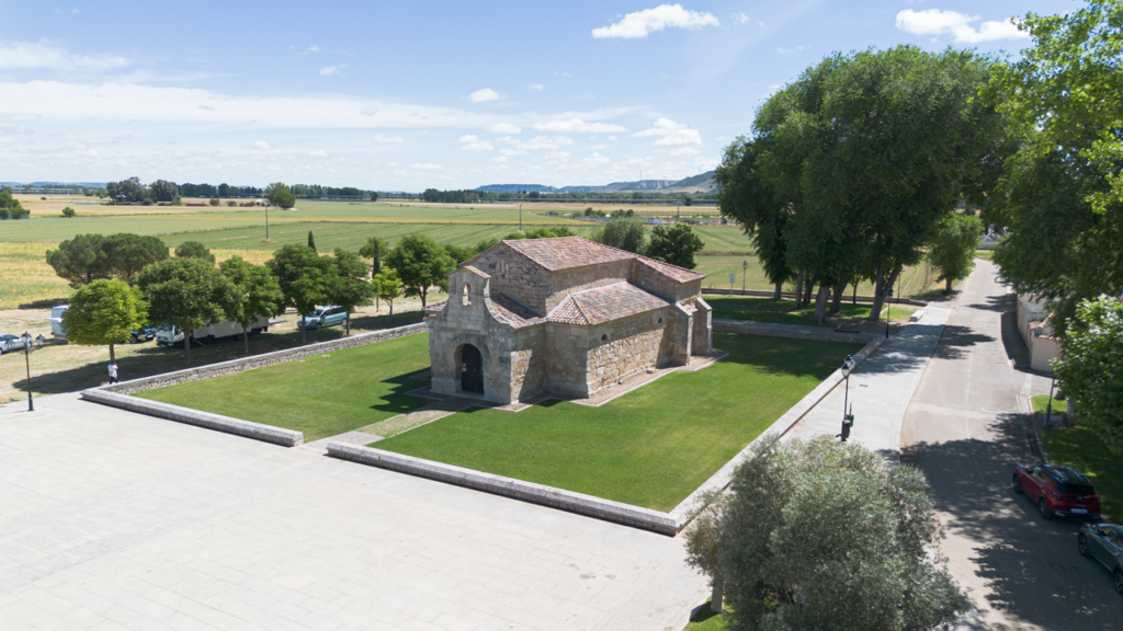 Panorámica de la basílica de San Juan Bautista, rodeada de árboles. Destaca su entrada con arco de herradura.