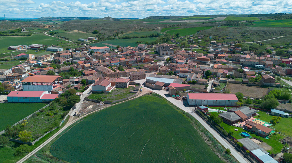 Panorámica aérea de Herrera de Valdecañas, destacan la iglesia y el cerro de las bodegas. Al fondo se aprecia la ermita de la Virgen de los Remedios.