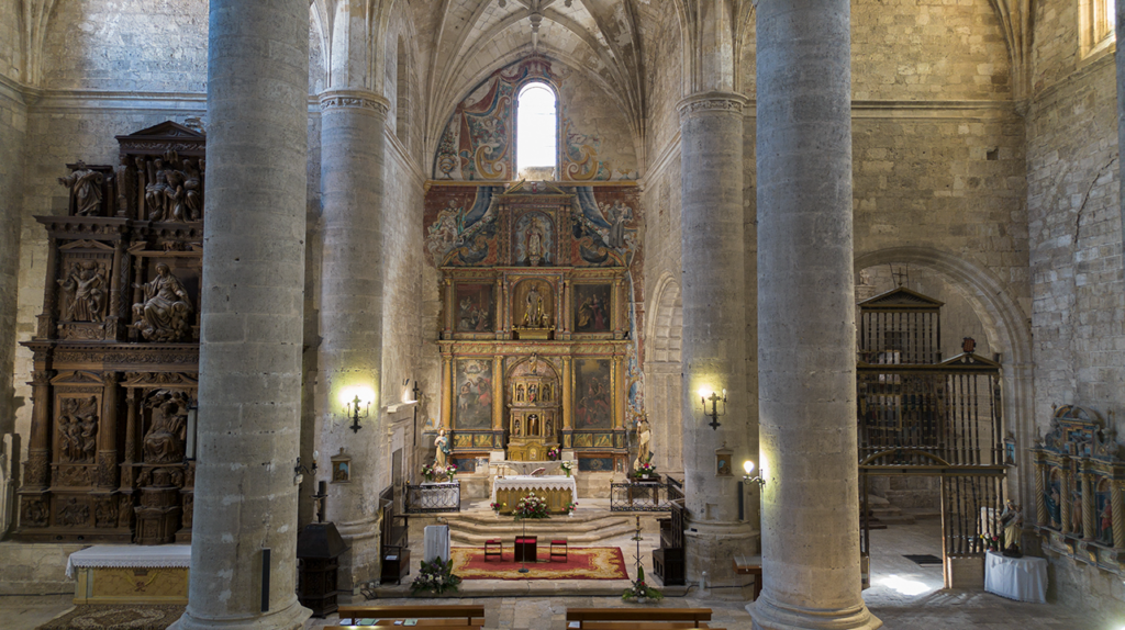 Interior de la iglesia de San Juan de Palenzuela. Al fondo el retablo mayor rencentista, compuesto mayoritariamente por lienzos pintados. Los muros tienen pinturas que simulan un lienzo que rodea al retablo.