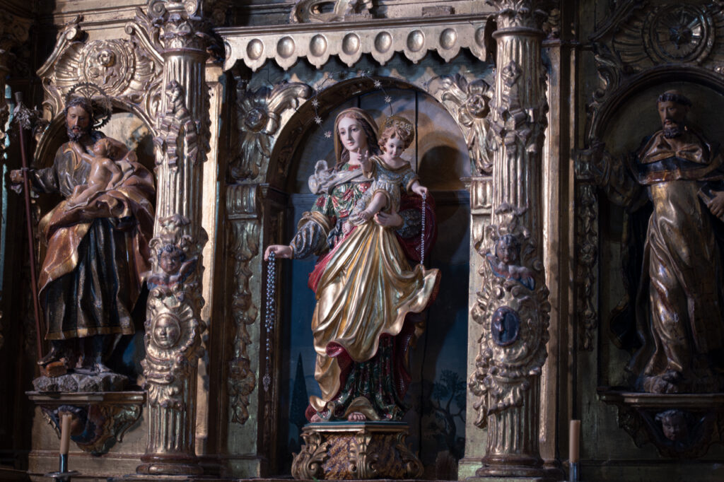 Escultura de la Virgen con el Niño en uno de los retablos laterales de la iglesia de San Miguel de Hontoria de Cerrato. Ambos sotienen rosarios.