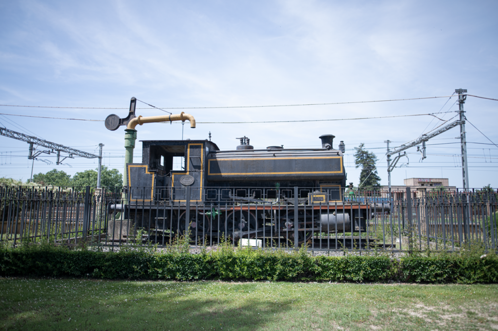 Locomotora a vapor marca Ebro expuesta como monumento al aire libre al lado de las vias del tren.