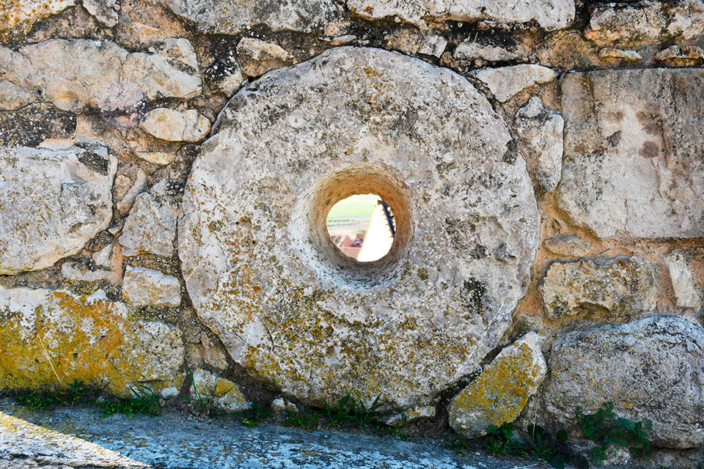 Detalle de una piedra de molino encastrada en un muro próximo a la iglesia de Santa María la Real de Cubillas de Cerrato.