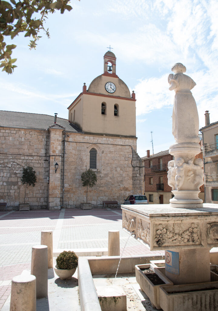 Torre de la iglesia de Nuestra Señora de la Asunción con la fuente de la plaza en primer término.