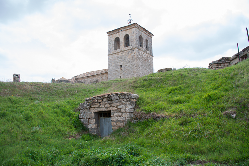 En primer término una de las entradas a las bodegas en la ladera del cerro sobre la que se alza la iglesia de San Nicolás de Bari, al fondo de la imagen.