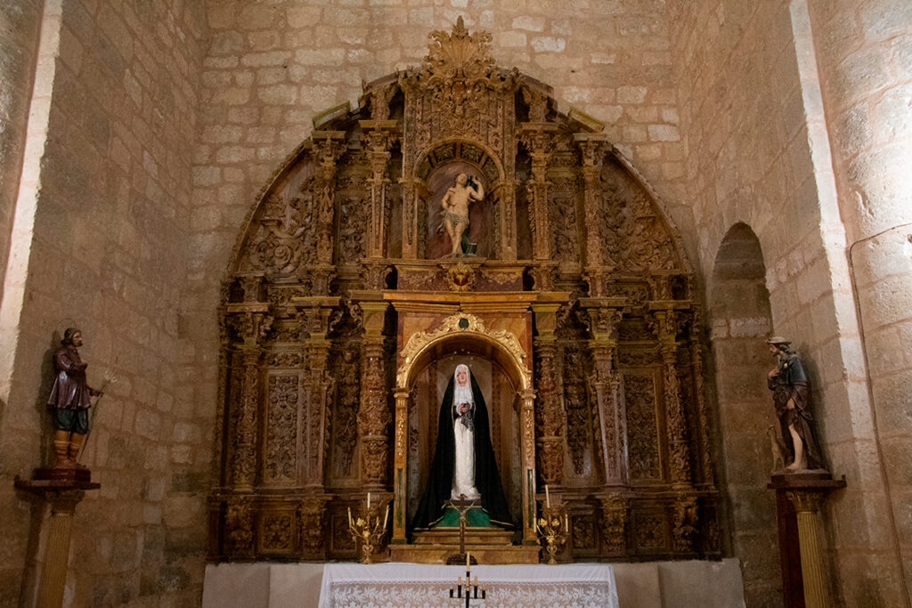 Retablo lateral barroco profusamente decorado presidido por una imagen de la Virgen y una talla de San Sebastián en el atrio.