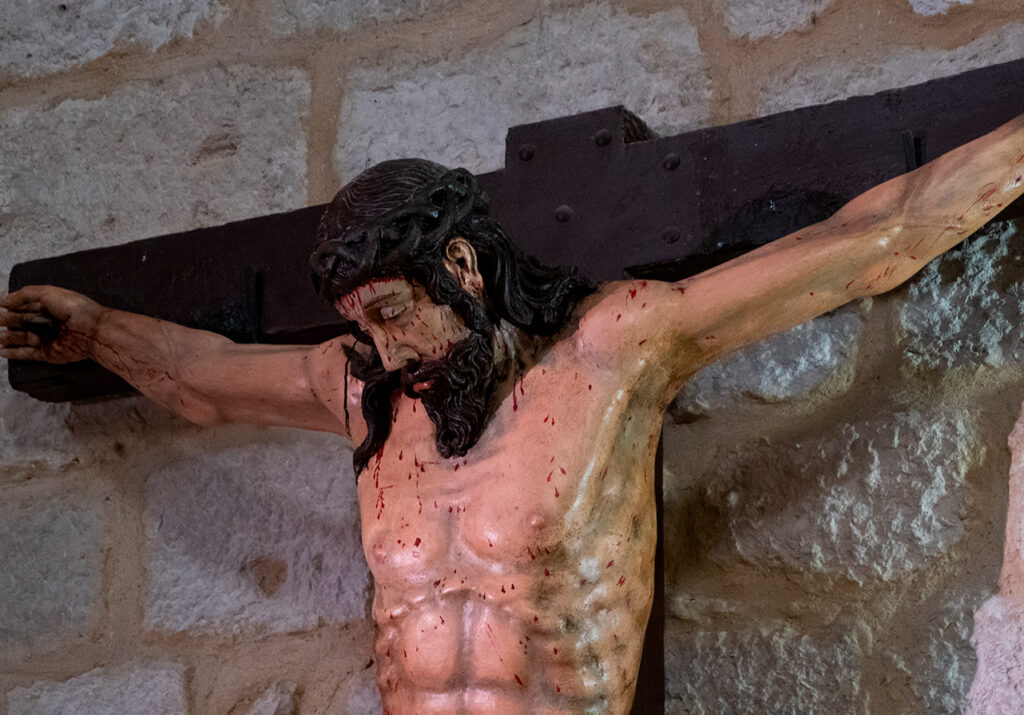 Detalle de un Cristo crucificado anclado a la pared de la iglesia de San Román de Cobos de Cerrato.