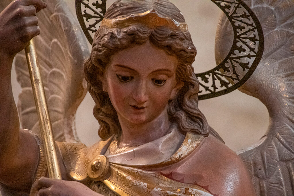 Detalle de una escultura en yeso policromado de un ángel sosteniendo un estanderte en el interior de la iglesia de San Miguel Arcángel de Hornillos de Cerrato.
