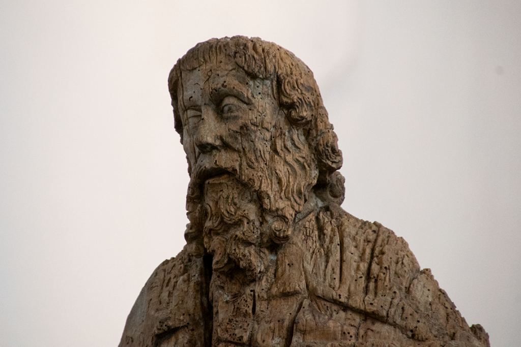 Detalle del rostro de una escultura tardogótica de un santo barbado indeterminado. Está realizada en madera, muy afectada por las termitas y no conserva policromía.