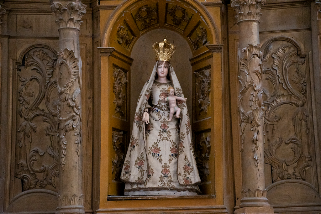 Detalle de una virgen de vestr acompañada del niño Jesús, que sostiene un rosario.