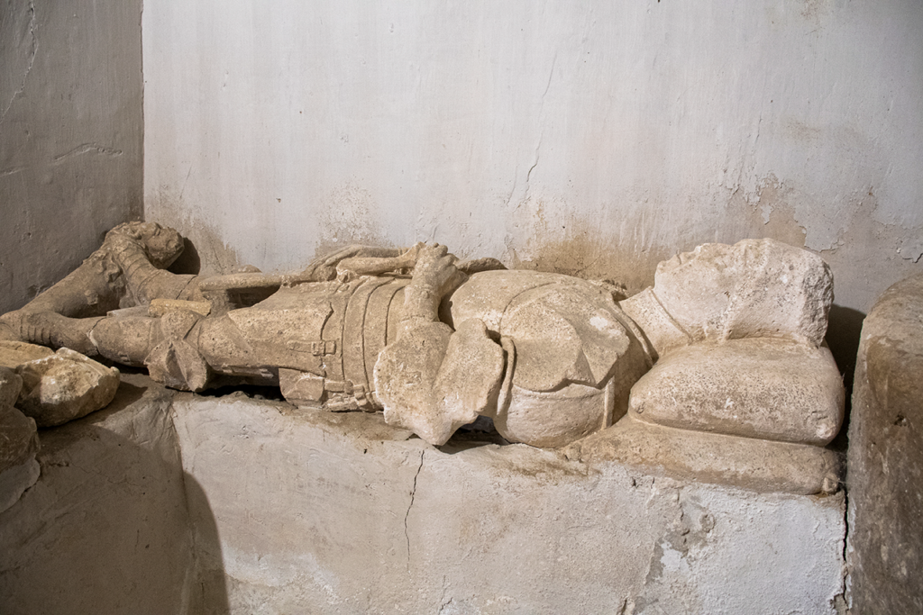 Sepulcro de un noble de finales del siglo XV, que viste armadura completa y tiene un perro a sus pies.