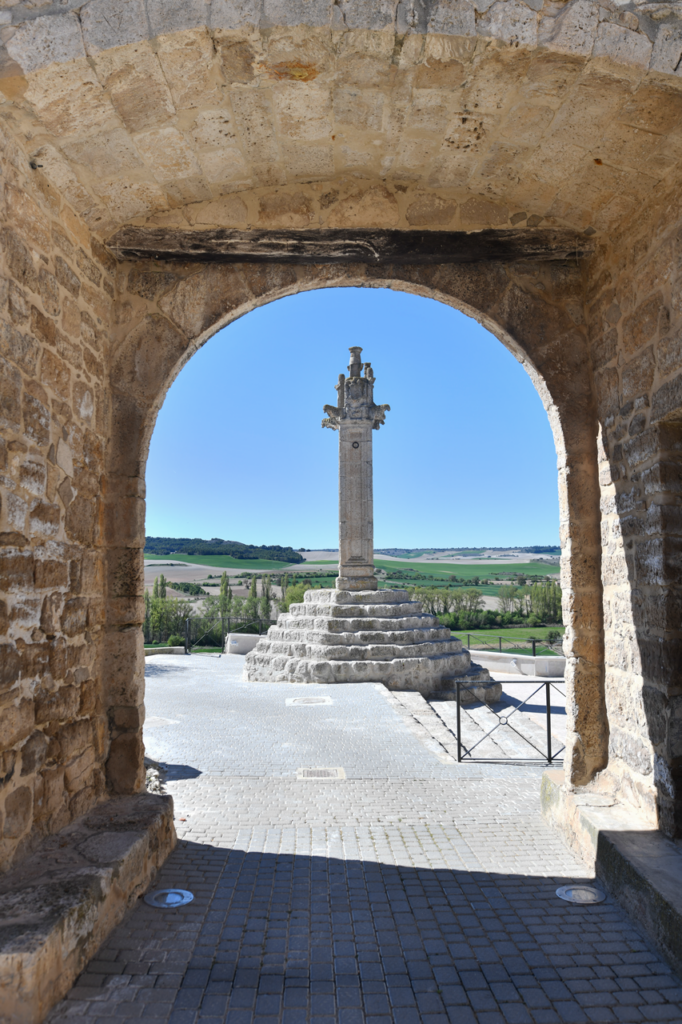 El rollo de justicia de Vertavillo enmarcado por la puerta de la muralla y los valles del Cerrato desplegados al fondo.