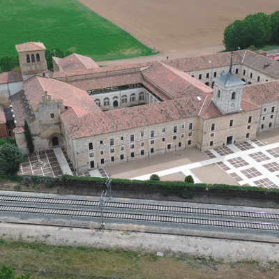Panorámica aérea general del Monasterio de San Isidro de Dueñas, con las vías del tren frente al edificio.