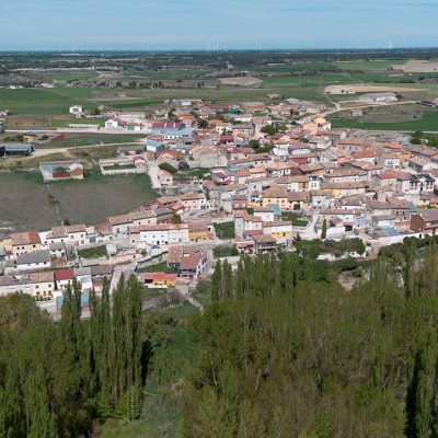 Panorámica aérea de Hérmedes de Cerrato, asentado sobre la ladera del páramo. En primer término la frondosa arboleda que puebla la vega del Arroyo Maderón.