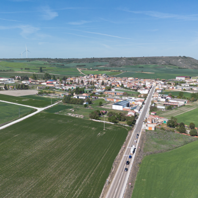 Panorámica aérea de Villaviudas, rodeado de campos de cultivo. Al fondo los páramos, sobre los que se alzan aerogeneradores.