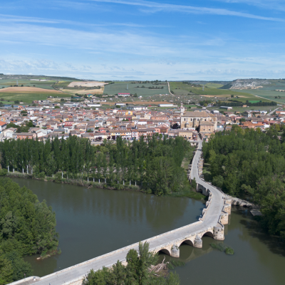 Panorámica aérea de Torquemada. En primer término el puente medieval sobre el río Pisuerga, a continuación la iglesia de Santa Eulalia y al fondo el barrio de bodegas.